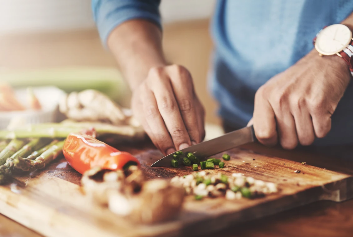 Person slicing green onions in kitchen